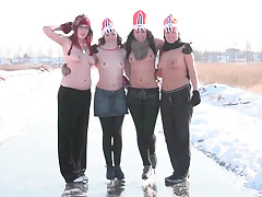 4 bare-chested squealing on skates are standing on a frozen cavern in the middle of snowy fields. Holding each others forearms they start to skate around. After posing for the photographer they disrobe fully and skate on.